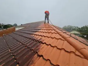 Roof repair in progress with technician fixing broken roof tiles on residential home